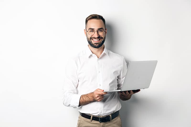Business. Sucessful businessman working with laptop, using computer and smiling, standing over white background.